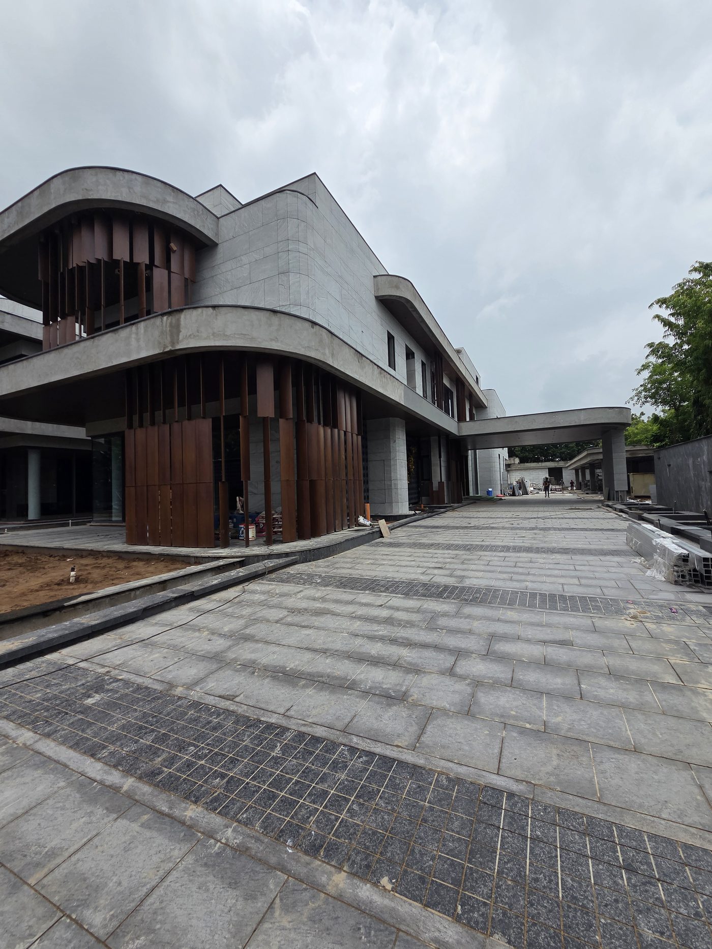 Amanat Residence under construction, showing curved concrete architecture and timber screen facade, Ahmedabad