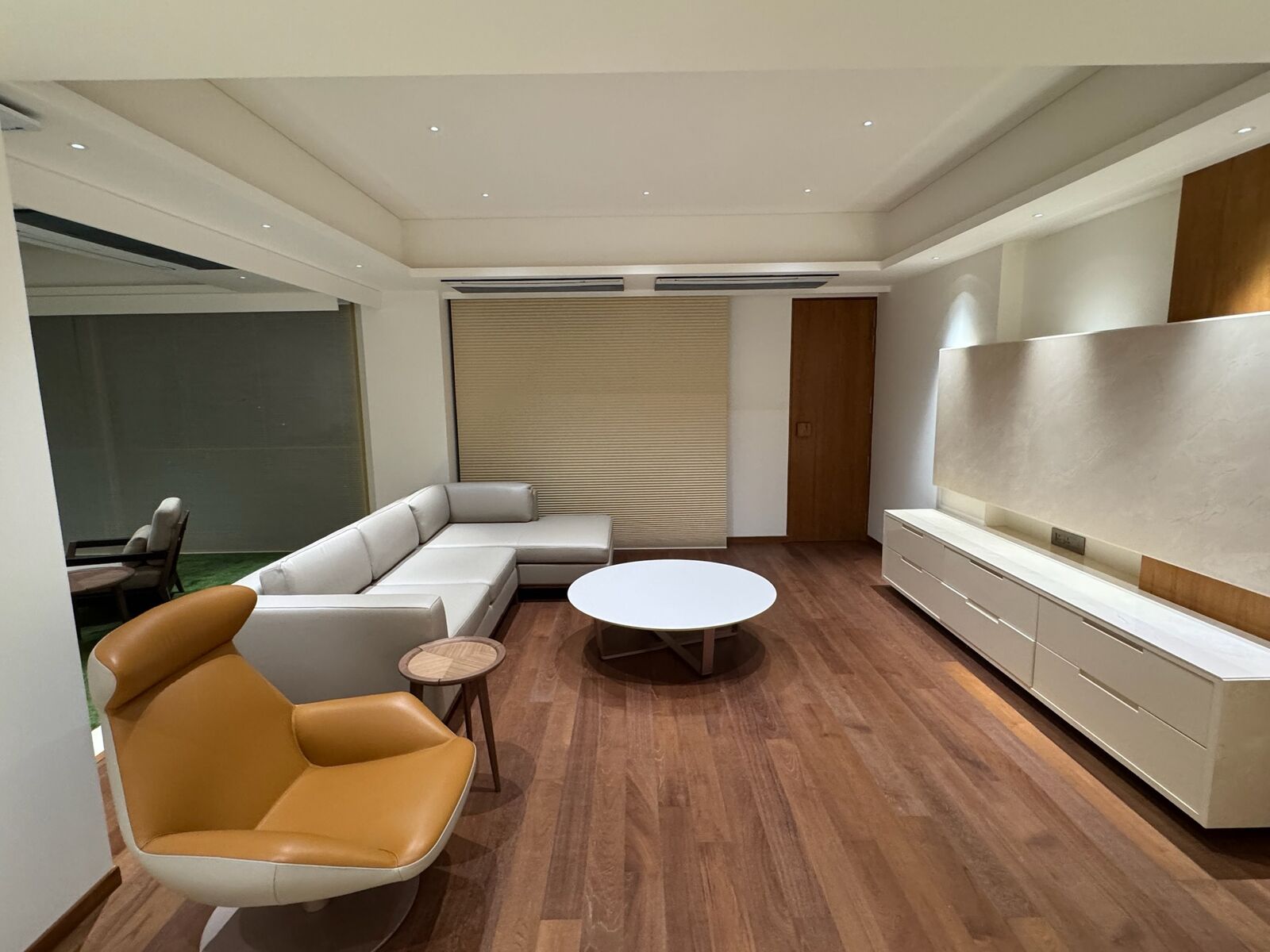 J. Bhalodia Residence living room with wood flooring and wall-mounted TV console