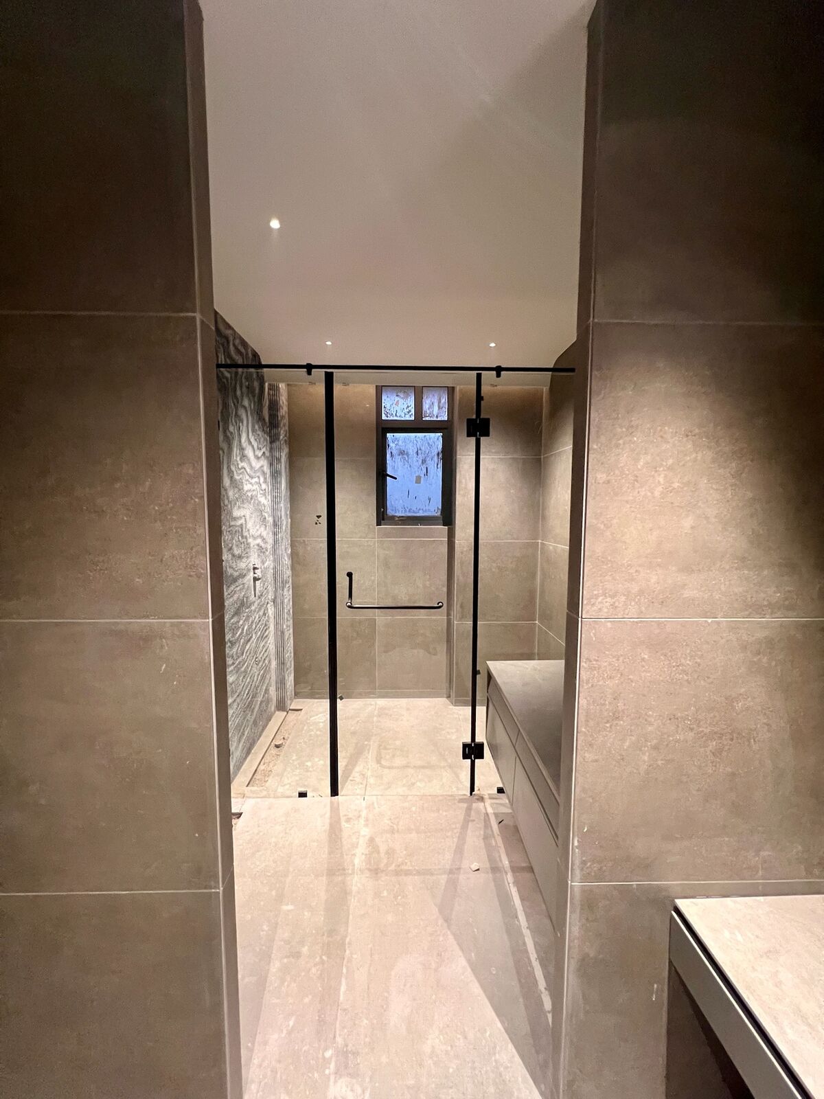 Emberlynn bathroom under fit-out, glass shower enclosure and stone tile