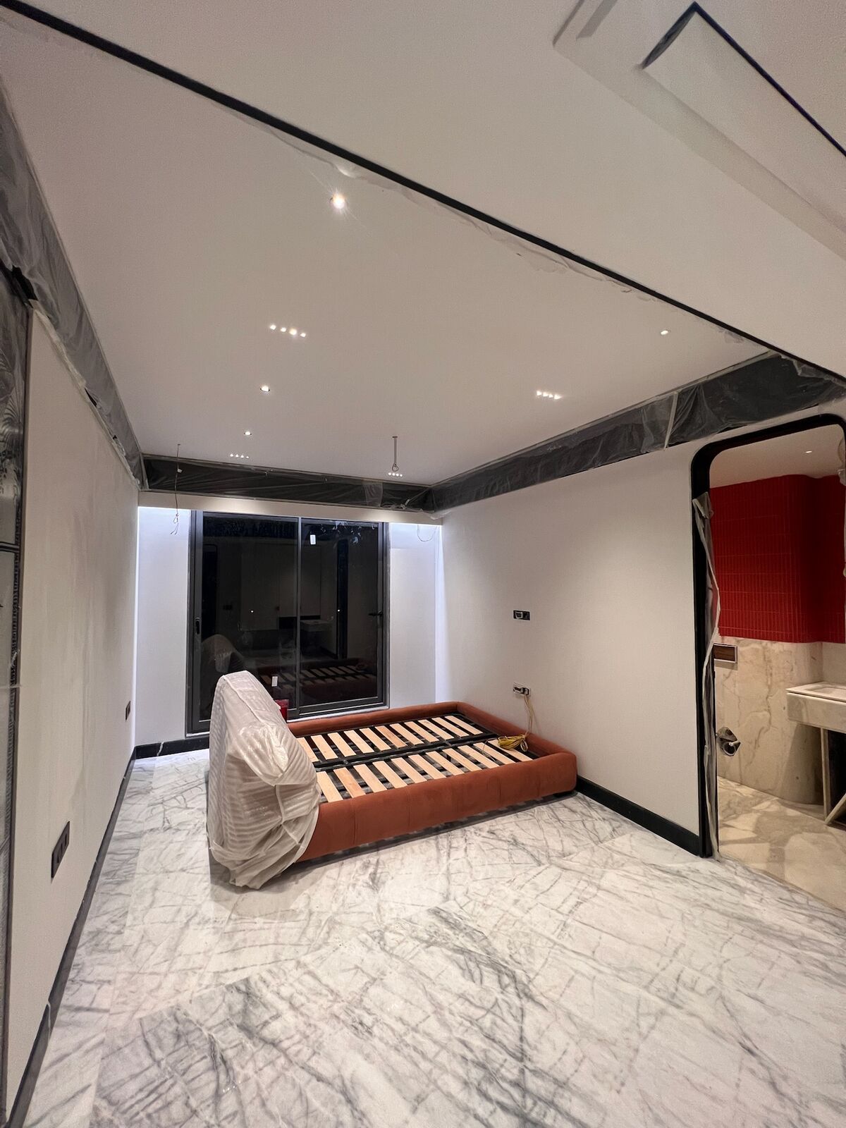 Emberlynn living area mid fit-out, furniture wrapped for protection, patterned marble flooring