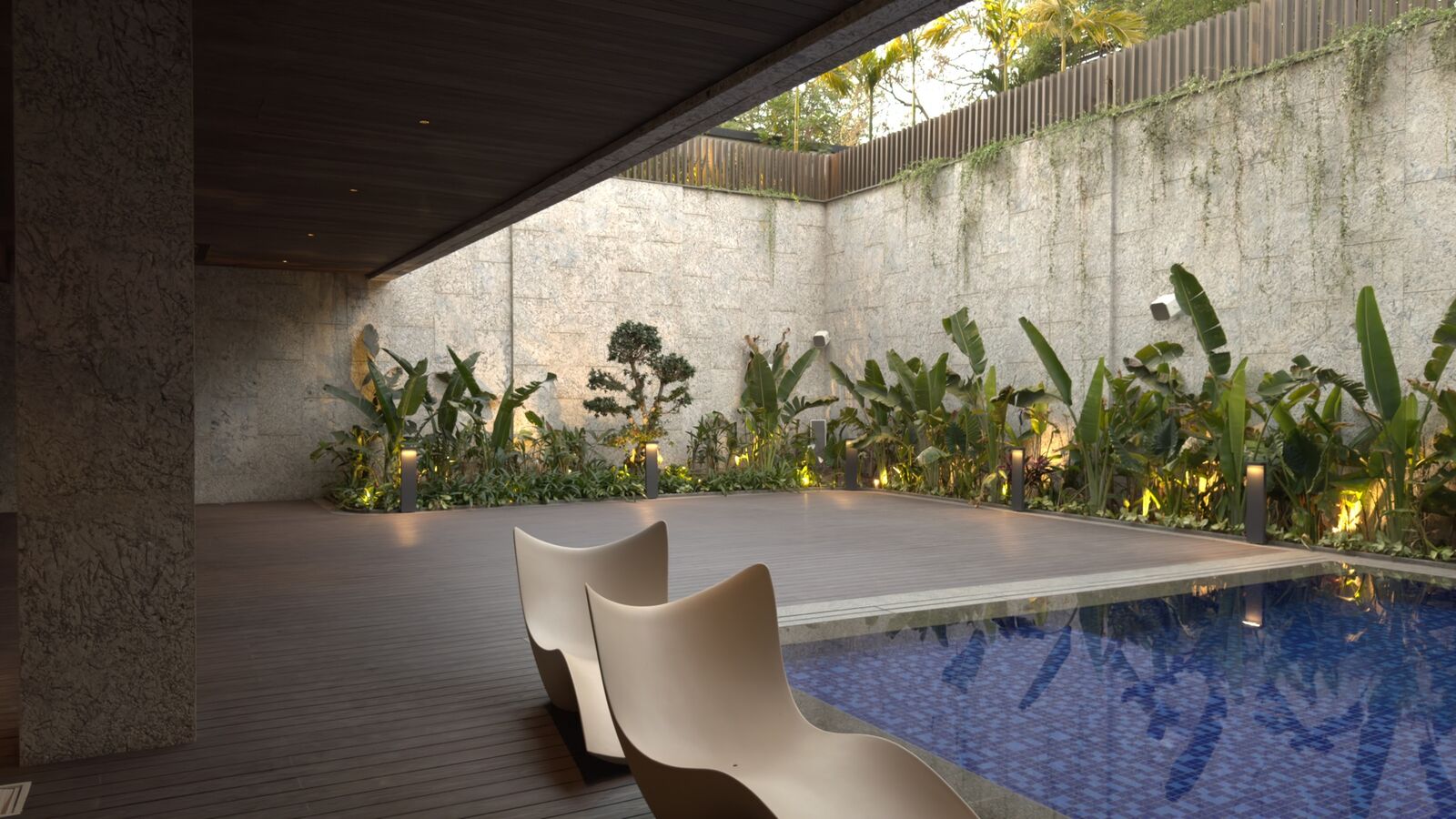 Poolside deck lounge with integrated landscape lighting at the Rohan Kataria residence
